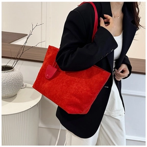 Detail of red matte leather tote bag with round charm and minimalist shoulder strap