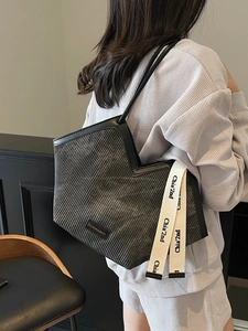 Deep grey tote bag with vertical ripple texture and decorative ribbon strap shown on model