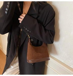 Gros plan du sac porté épaule en daim marron avec logo sur un mannequin en manteau noir