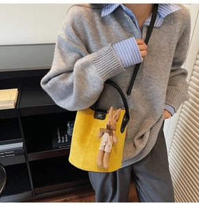 Detail of yellow suede bucket bag with black leather trim and cute rabbit pendant charm