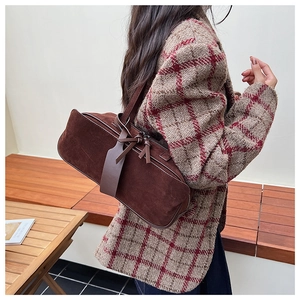 Close-up of brown suede pillow bag with matching trim on a wool coat outfit