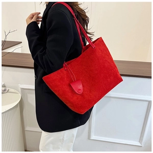 Detail of red suede tote bag worn with a black blazer showing its large capacity and texture