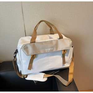 Close-up of a large capacity cream travel bag with buckle detail on a black leather chair