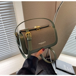 Dettaglio ravvicinato della borsa in pelle verde scuro con fibbia a conchiglia e oro