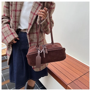Detail view of brown frosted suede pillow bag with dual zippers and leather tags