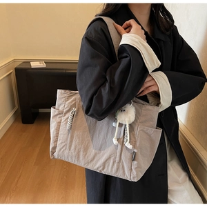 Detail of nylon tote bag with plush keychain accessory and smooth zipper closure