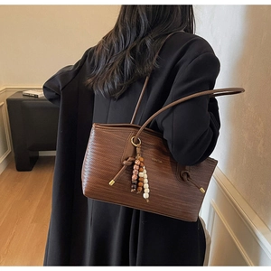 Detail of dark brown woven tote bag with retro bead charms on minimalist shoulder strap