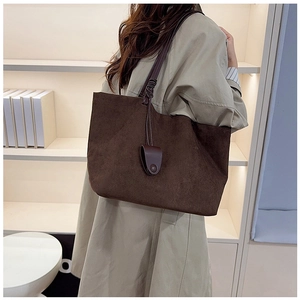 Detail of dark brown matte leather tote bag featuring a decorative woven knot handle