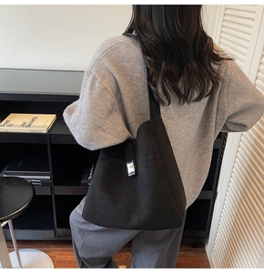 Detail of minimalist black hobo bag showing the silver metal buckle and soft suede texture