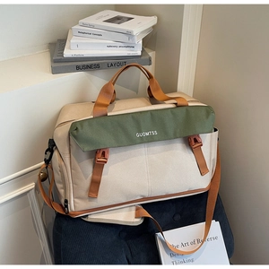 Detail of color-block travel bag with dual handles and adjustable strap on a chair