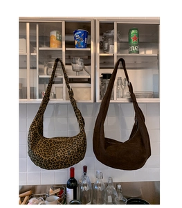 Detail of minimalist suede hobo bag and leopard print canvas shoulder bag in daily setting