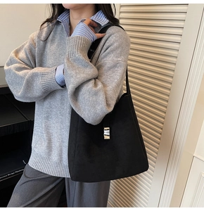 Detail of black suede hobo bag featuring a silver rectangular buckle and neat stitching
