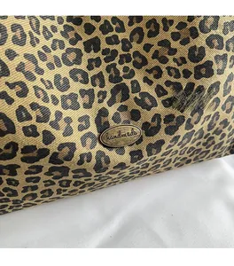 Close-up of leopard print tote bag fabric with antique bronze handmade metal tag