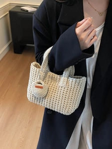 Beige handmade knitted handbag featuring a textured bucket style and a hand made leather tag
