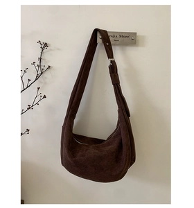 Detail of soft dark brown suede hobo bag with adjustable strap and metal hardware