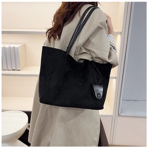 Detailed side view of black suede tote bag with slim straps and matching small pouch