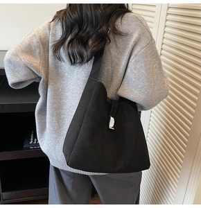 Detail of a large black matte hobo bag with a silver buckle worn by a person
