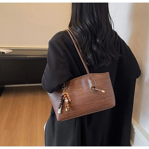 Detailed back view of a brown woven leather tote bag with stylish charm on model