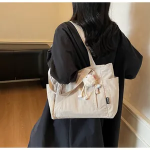 Detail of beige nylon tote bag with Fashion label and white fluffy bunny charm