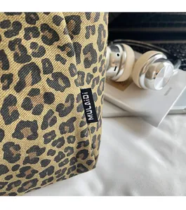 Detail shot of leopard print canvas tote bag showing fine stitching and side brand label