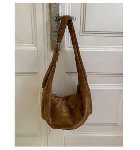 Detailed macro view of the brown suede crescent bag with silver metallic zipper closure