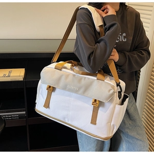 Detail of large travel bag showing front buckle closure and contrast shoulder strap