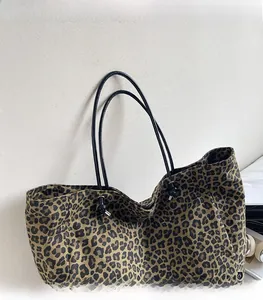 Detail of leopard print tote bag showing black shoulder straps and drawstring closure