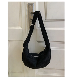 Detail of black suede hobo bag with adjustable silver buckle and metal zipper closure