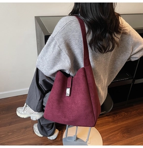 Detail of burgundy suede tote bag featuring a silver metal buckle and wide strap design