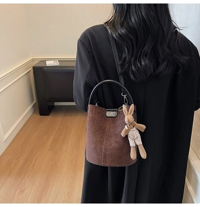 Detail of brown frosted bucket bag with round handle and cute rabbit plush charm