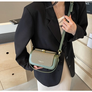 Dettaglio della borsa a tracolla in pelle verde scuro con chiusura dorata e texture