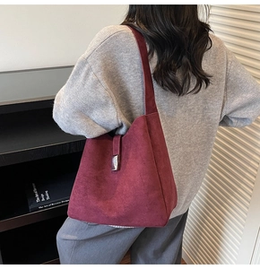 Close-up of wine red suede bucket bag with silver metal buckle on a shoulder model