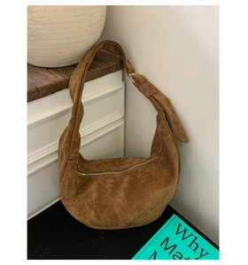 Close-up of brown suede hobo bag featuring silver zipper and adjustable buckle strap