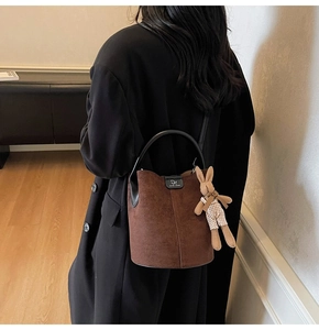 Detail of dark brown frosted bucket bag featuring a cute rabbit charm and metal DA logo