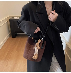 Brown suede bucket bag detail with black leather DM logo and a cute woven rabbit pendant