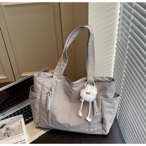 Close-up of lightweight nylon tote bag with side pockets and plush monster charm
