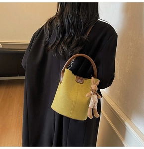 Detail of mustard yellow suede bucket bag featuring a cute bunny plush charm and DM logo