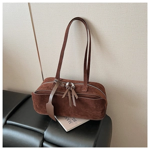 Detail of dark brown suede pillow bag featuring silver double zippers and leather tassels