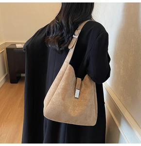 Side view of a large brown suede hobo bag with silver hardware on a black coat