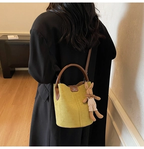 Detail of mustard yellow bucket bag with brown handles and a cute bunny charm accessory