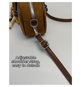 Dettaglio della tracolla regolabile e rimovibile di una borsa Boston in camoscio marrone