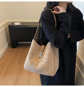 Detail of minimalist khaki suede bucket bag featuring a silver metal buckle and wide strap