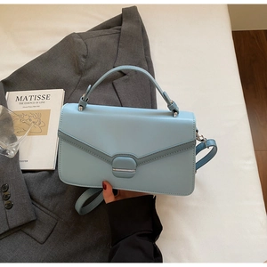 Close-up of light blue matte leather handbag with silver clasp and adjustable shoulder strap