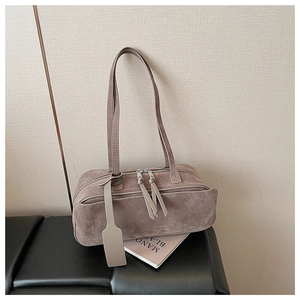 Detail of taupe suede pillow bag with metal zipper and long leather tassel charm