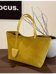 Minimalist large yellow tote bag with matte finish and matching pendant on a wooden table