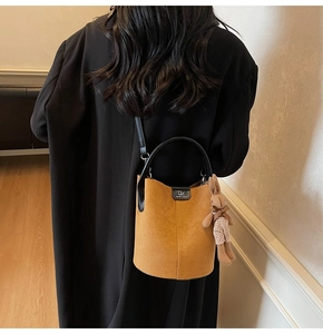 Detail of a brown frosted bucket bag with a cute rabbit pendant and black handles