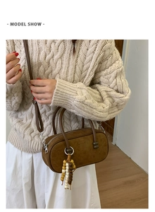 Dettaglio della borsa Boston in camoscio marrone scuro con nappa di perline in legno e zip