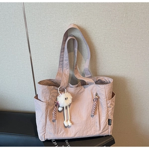 Detail of rose pink nylon tote bag with front zipper, side pockets and plush charm