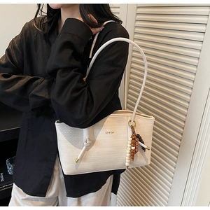 Detailed view of white woven texture tote bag with shoulder strap and bead charm
