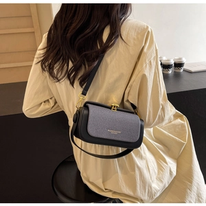 Modella che indossa una borsa a tracolla strutturata nera e grigia con chiusura dorata